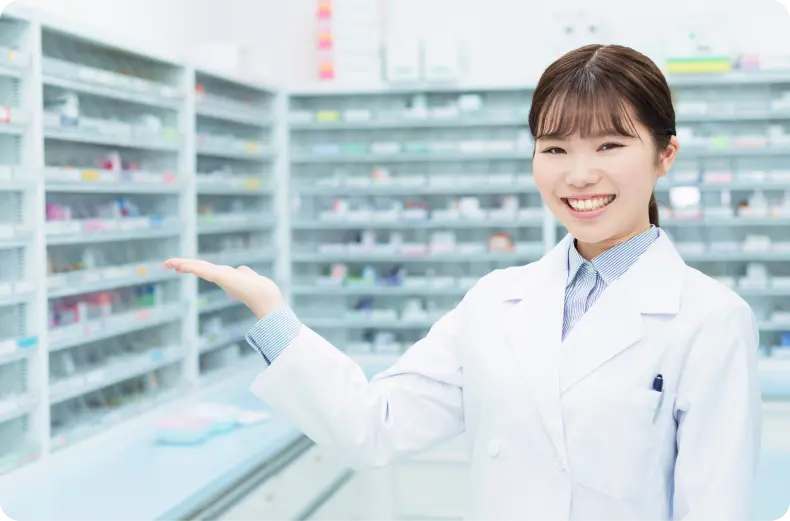 女性薬剤師が薬局内で笑顔で手を広げて案内している様子