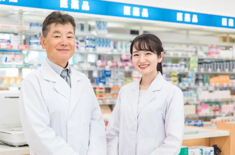 薬局内で2人の薬剤師が笑顔で並んで立っている様子
